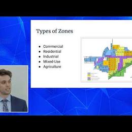 Video still of a presenter beside a slide titled "Types of Zones" with a city zoning map.